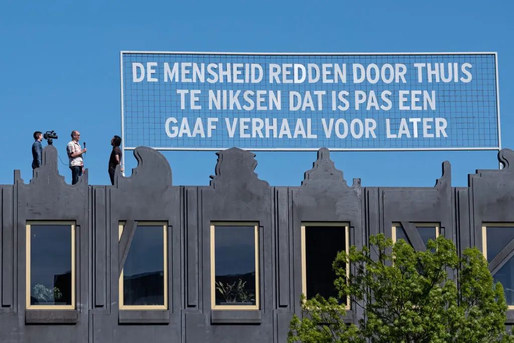 Tekstbord op Dara met tekst: De mensheid redden door thuis te niksen dat is pas een gaaf verhaal voor later